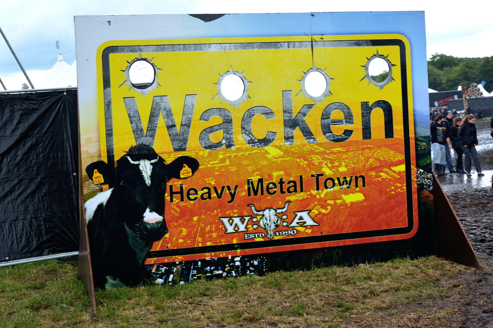 Stort orange skilt med enorme kulehull i: Wacken, Heavy Metall Town.